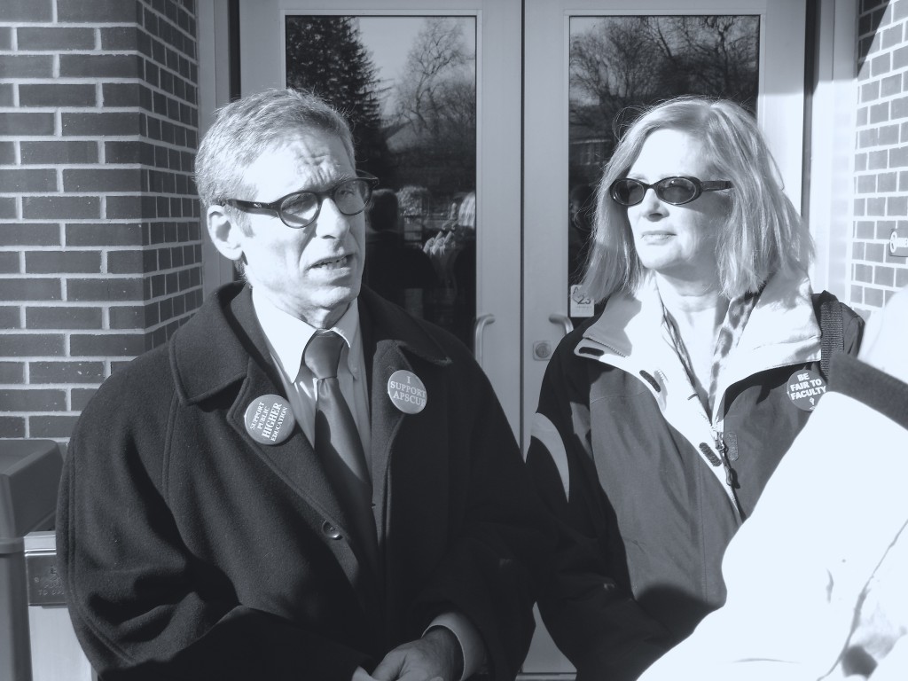 Dr. Alan Benn and Dr. Nancy Van Arsdale talk to students and faculty at a faculty march. Photo Credit / Jamie Reese
