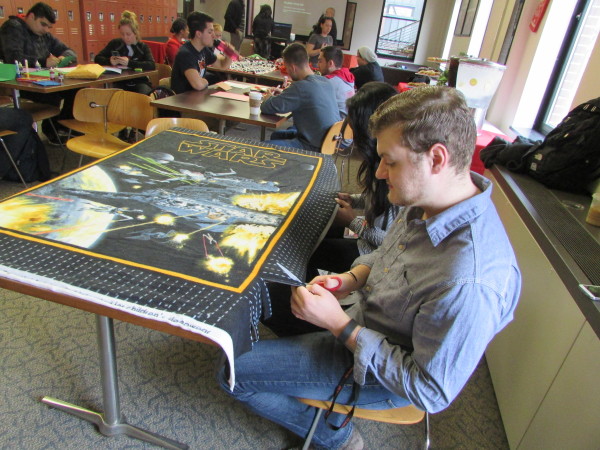 Student Senator Louie Wein puts his scissors to work on a no-sew blanket. Photo Credit / Madison Petro
