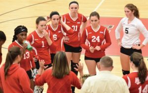Junior libero #5 Rosa Veliky (in white) and the team listen to Coach Allison Keeley during a timeout. Photo Credit / Ronald Hanaki
