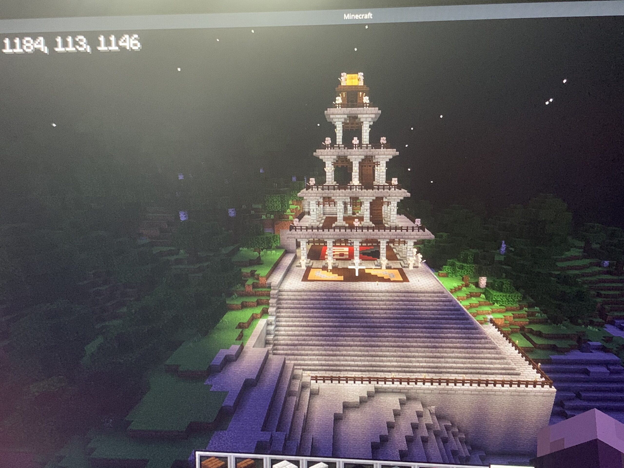 A glowing pyramid-like structure partly in a forest leading to a river in Minecraft