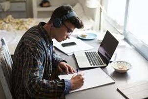 Man with headphones studying with laptop and notebook