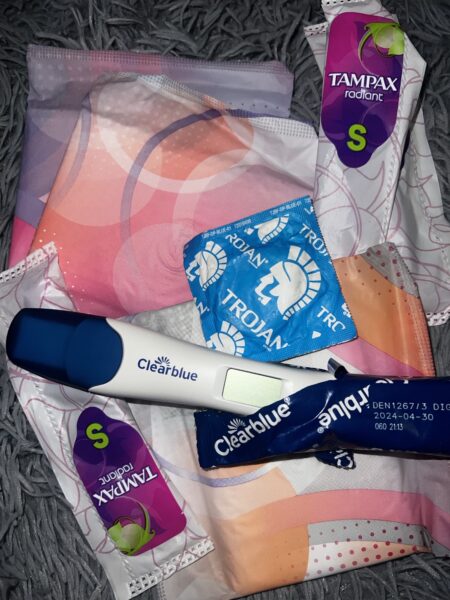 Image of pregnancy test, condoms, period pads, and tampons (Photo Credit: Nyah Acklam)