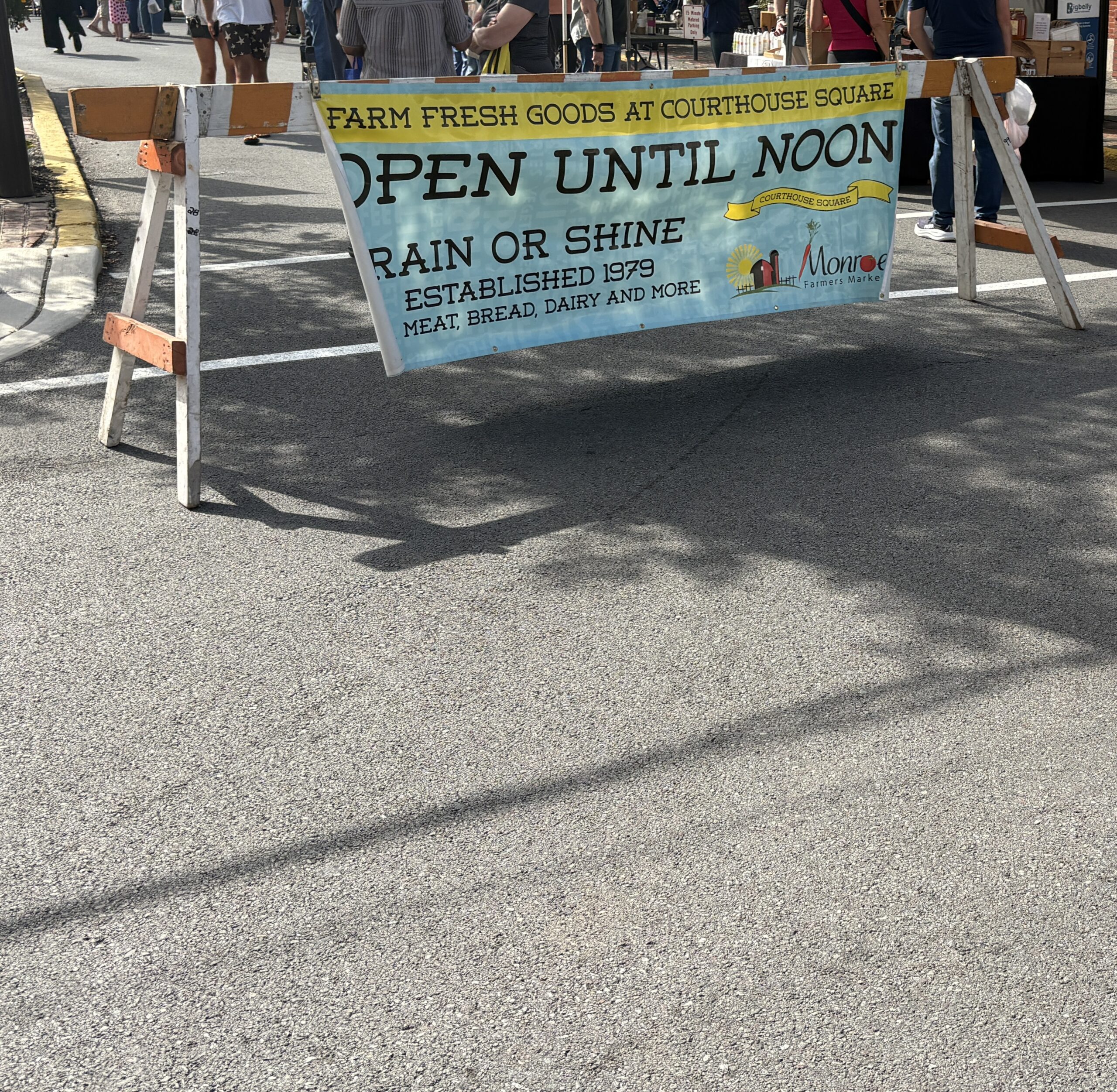 Blue Monroe Farmers market banner stating open until Noon
