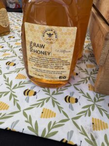photo of jar of raw honey on a cloth decorated with bees and bee hives